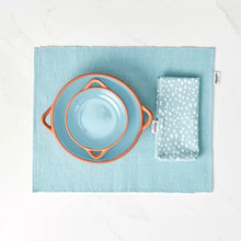 Load image into Gallery viewer, Two glazed terracotta tapas dishes in blue and orange colors, displayed on a matching cotton placemat with a white and blue patterned napkin to the side.