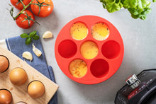 Load image into Gallery viewer, red silicone egg bites mould shown from above with eggs on a worktop with eggs tomatoes and herbs