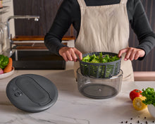 Load image into Gallery viewer, Person using a salad spinner with a kitchen setting in the background
