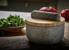Load image into Gallery viewer, Granite Pestle and Mortar with bamboo lid on a wooden surface with vegetables in the background