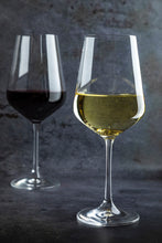 Load image into Gallery viewer, Two wine glasses, one with red wine and one with white wine, on a dark background.