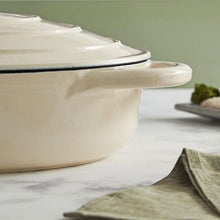 Load image into Gallery viewer, A green cast iron casserole dish with lid and two handles on a kitchen counter. cream colour.