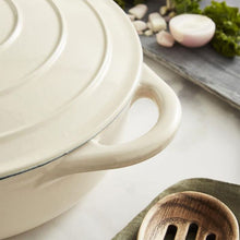 Load image into Gallery viewer, A green cast iron casserole dish with lid and two handles on a kitchen counter. cream colour.