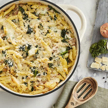 Load image into Gallery viewer, A green cast iron casserole dish with lid and two handles on a kitchen counter. containing pasta.