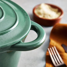 Load image into Gallery viewer, A green cast iron casserole dish with lid and two handles on a kitchen counter. close up and background.