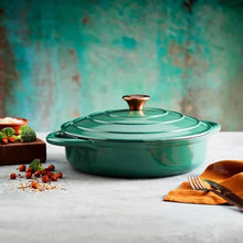 Load image into Gallery viewer, A green cast iron casserole dish with lid and two handles on a kitchen counter.