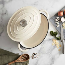 Load image into Gallery viewer, A green cast iron casserole dish with lid and two handles on a kitchen counter.