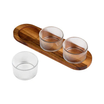 Three clear glass pinch pots on a wooden tray with a white background