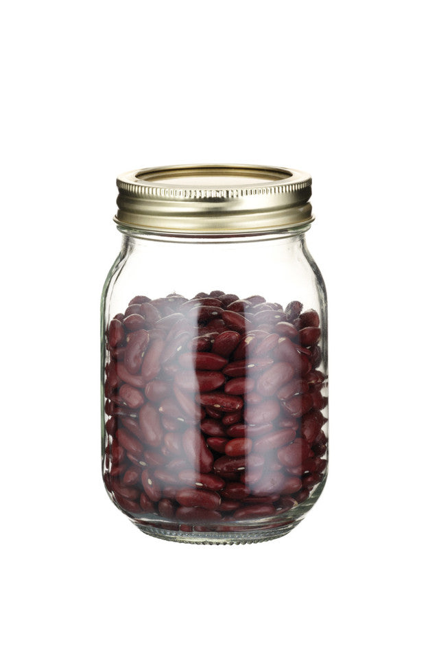 Glass jar with a gold lid filled with red beans on a white background