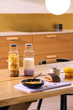 Load image into Gallery viewer, Breakfast setup on a wooden table with cereal, milk, and a sandwich.
