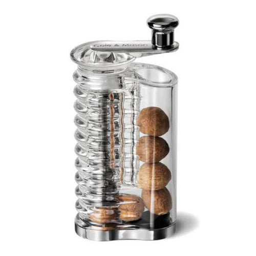 Clear nutmeg grinder with nutmeg stored inside on a white background