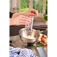 Load image into Gallery viewer, Person seasoning food in a bowl with a nutmeg grinder in a kitchen setting.
